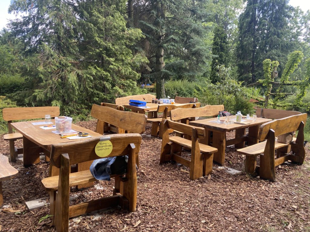 Foto, auf dem Holzbänke und -tische zu sehen sind, die in der Gartenarbeitsschule in Treptow-Köpenick stehen.